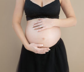 Close shot of baby bump of pregnant woman in black dress