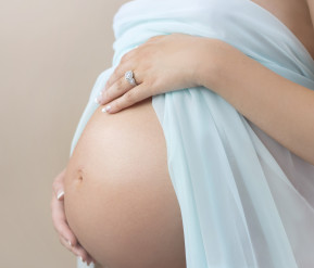 Baby bump of pregnant woman in sky blue dress