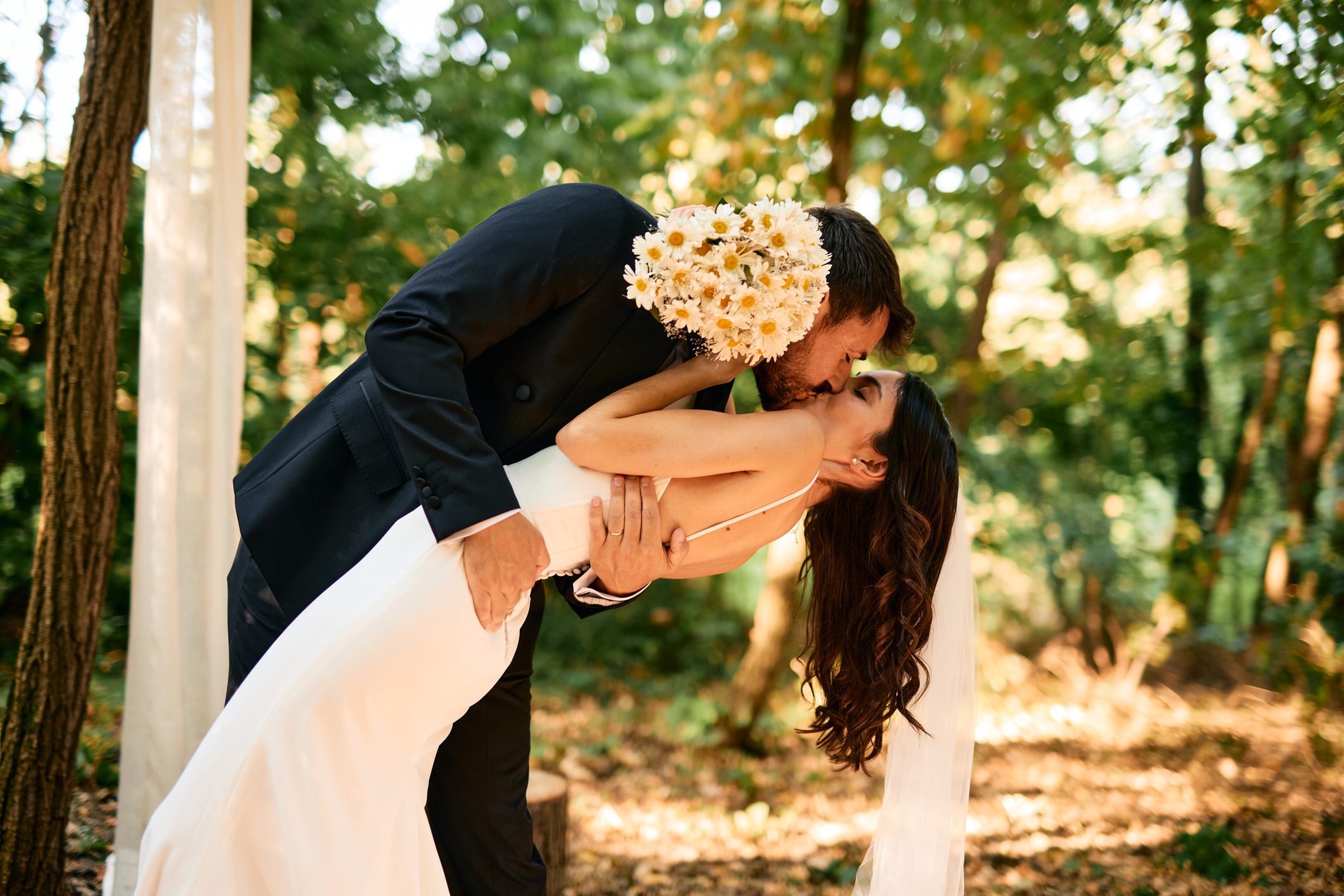Bride and groom kissing in forest