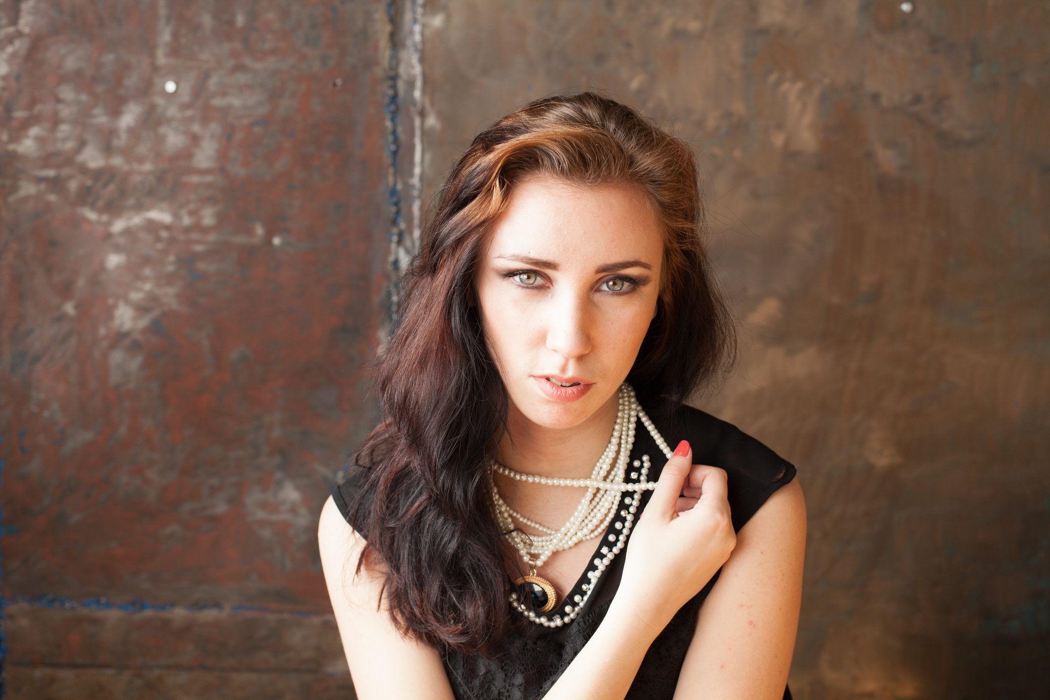 Brunette holding pearl necklace, serious expression