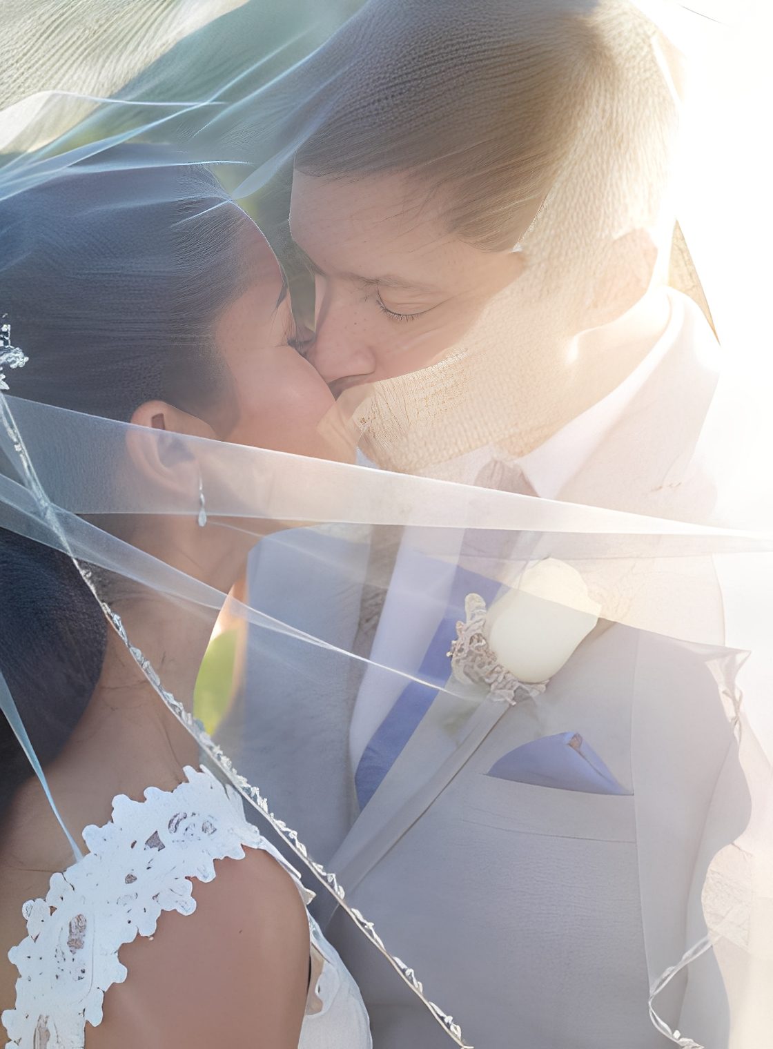 Bride and groom kissing under veil