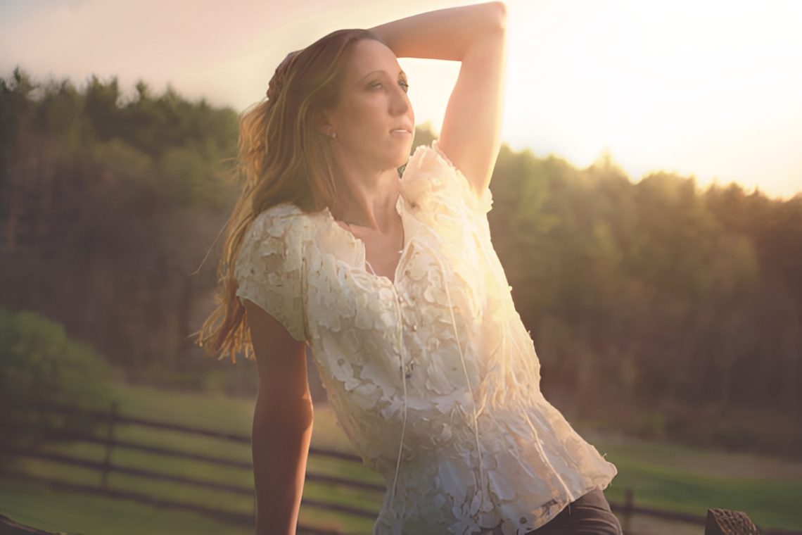 Sunlit woman leaning on fence