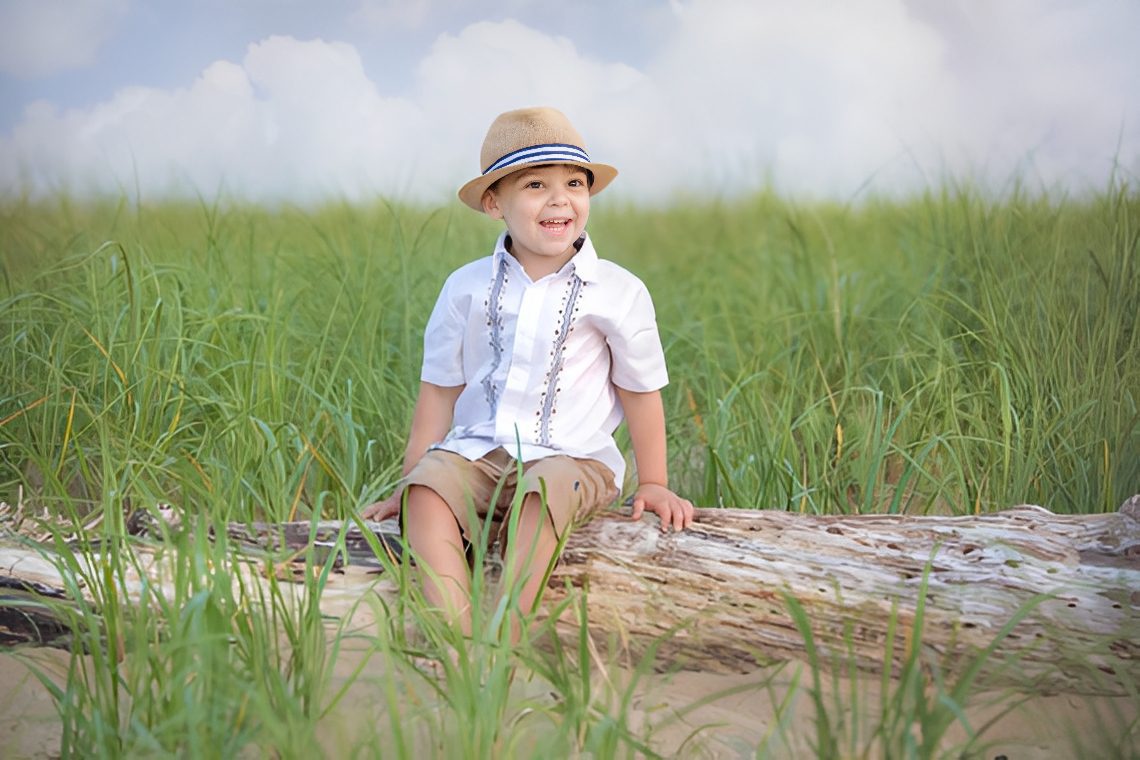 Boy wearing hat smiling outdoors.